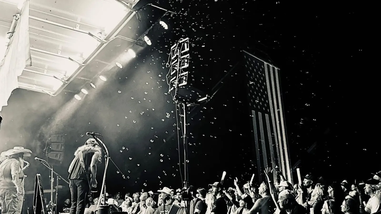 The crowd cheers below the stage as bubbles and lights fill the night sky