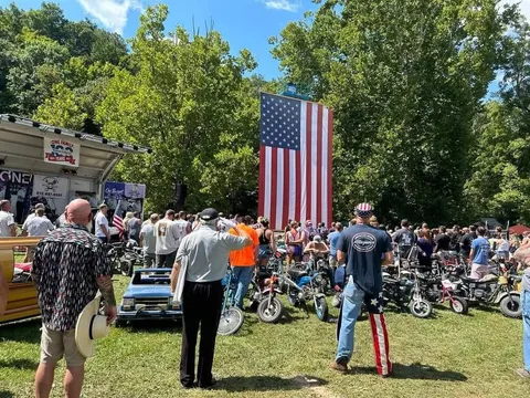 A crowd gathered before the giant American flag and rows of mini bikes for opening ceremonies
